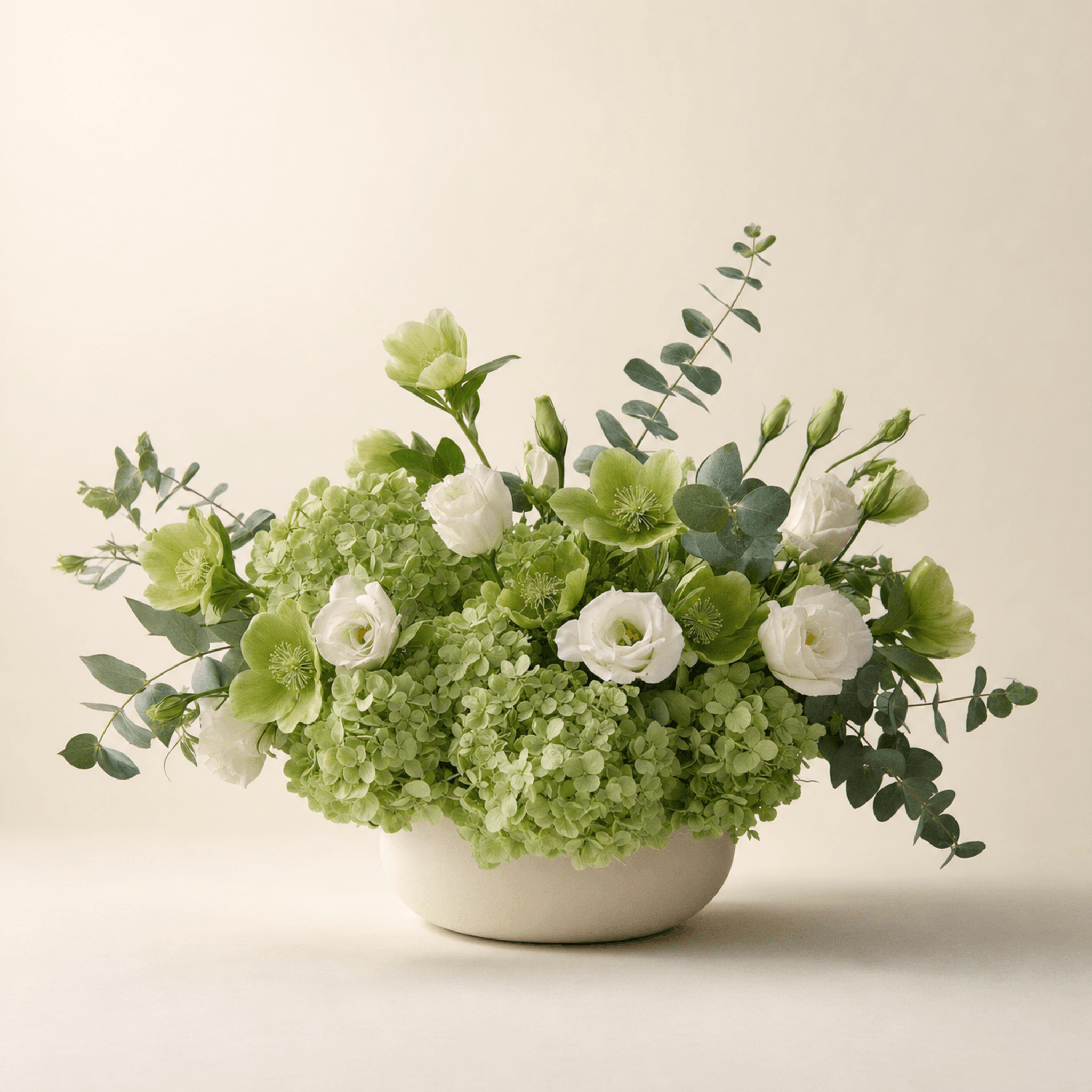 Green hydrangeas, white lisianthus, green hellebores and eucalyptus in a cream ceramic bowl